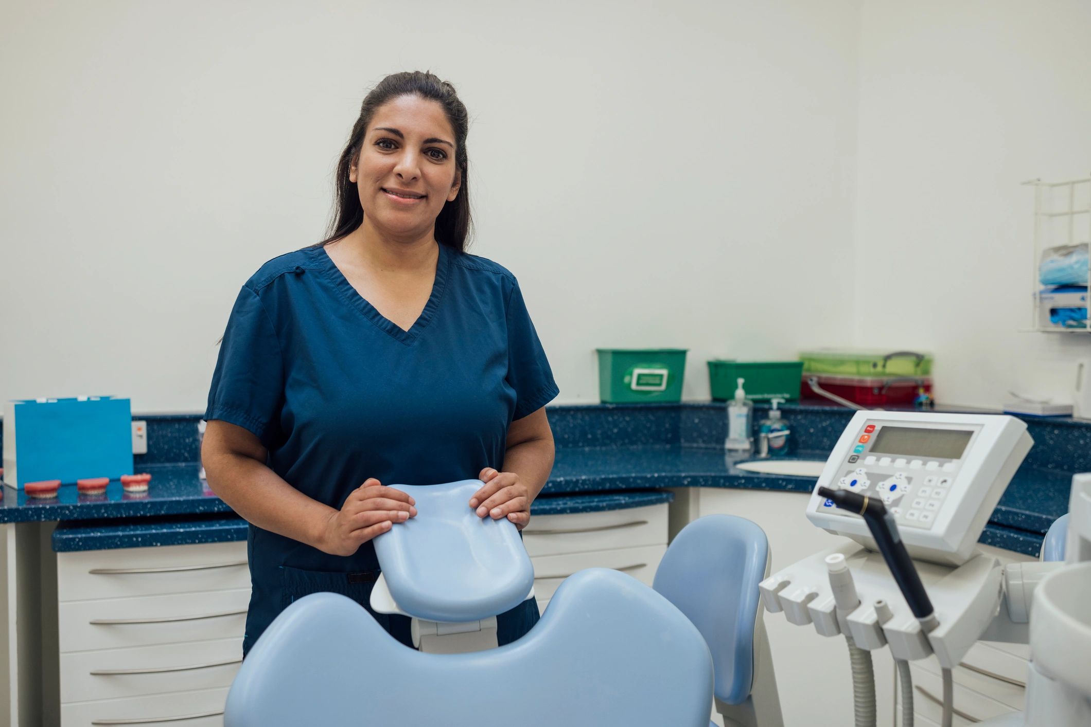 Dentist in a treatment room beside a dental chair